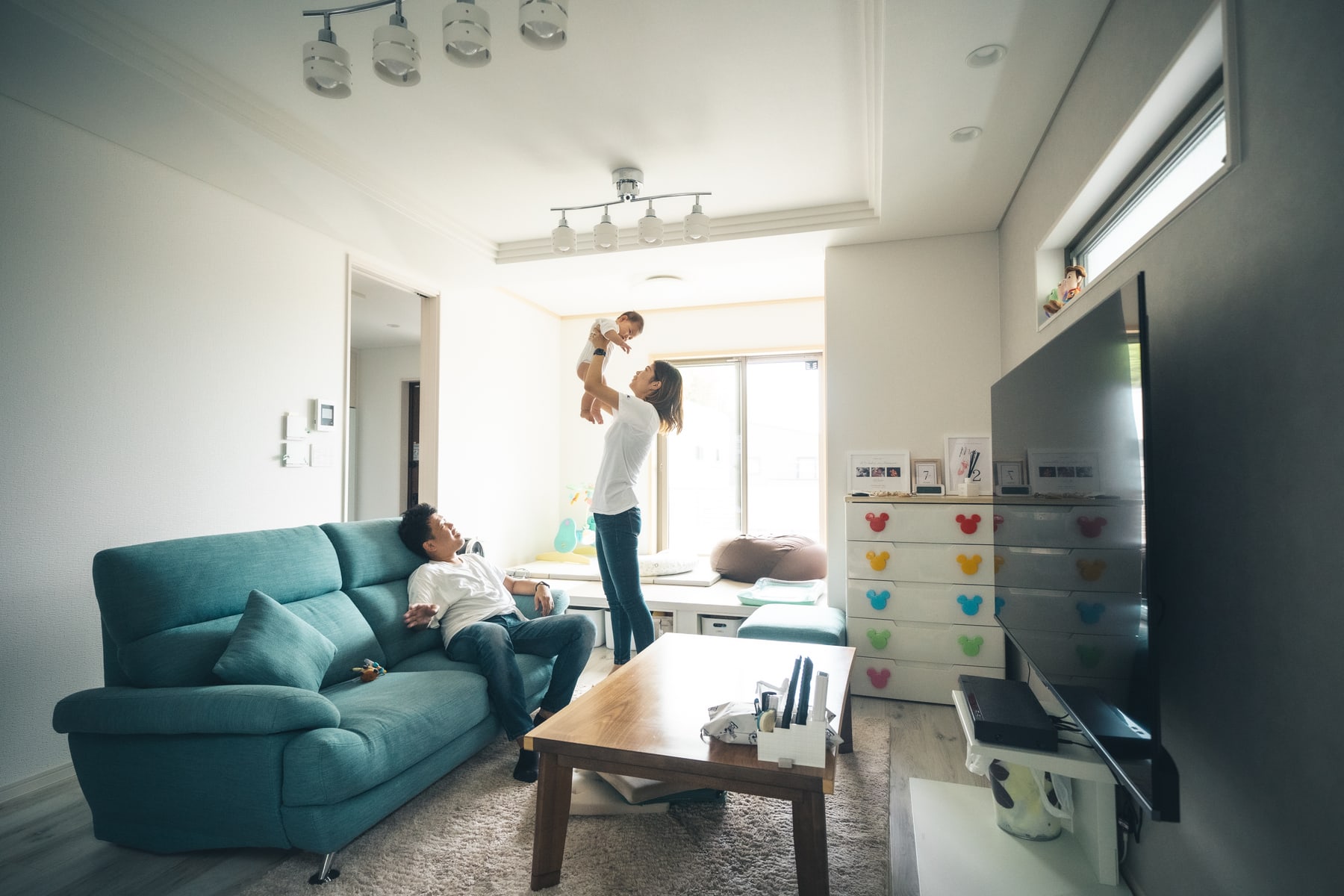 完成した住宅のリビングで、家族三人が自然に過ごす様子